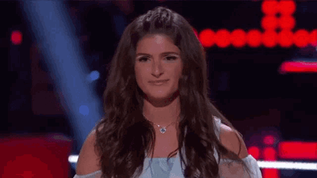 a woman with long brown hair is standing on a stage in front of a red background with the number 88 on it