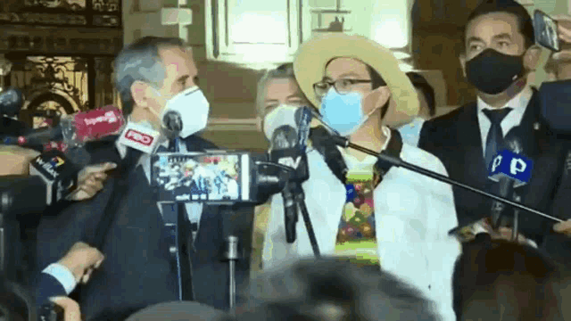 a group of people wearing face masks are standing in front of microphones with pd written on one of them