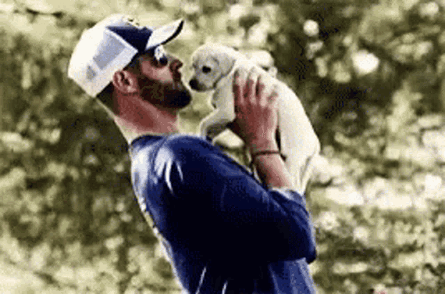 a man is holding a small white puppy in his arms .