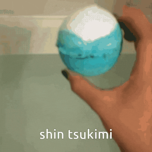 a person is holding a blue ball with the words shin tsukimi written on it