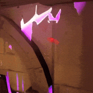 a purple light is projected on a wall with a silhouette of a bat on it