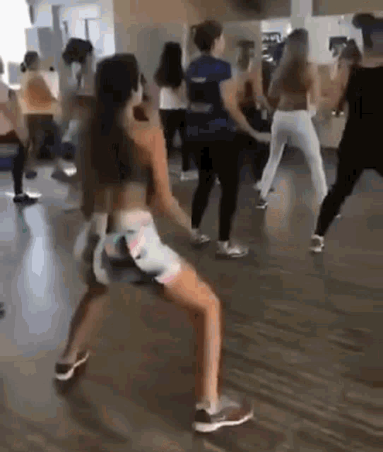 a woman is dancing in a gym with a group of women .