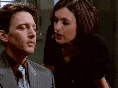 a man in a suit and tie talks to a woman