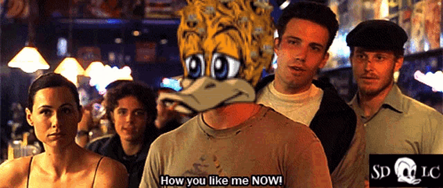 a group of people are standing in a dark room and one of them is asking how you like me now