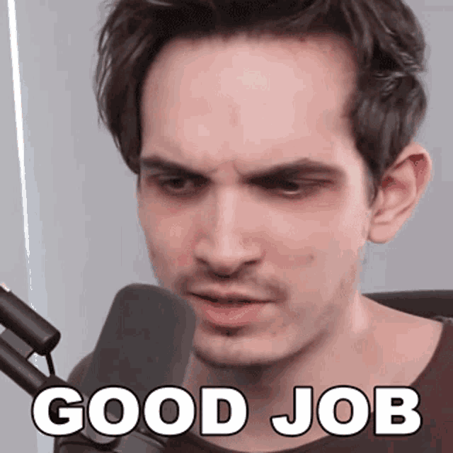 a man sitting in front of a microphone with the words good job above his head
