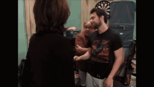 a woman is standing next to a man in front of a dart board .