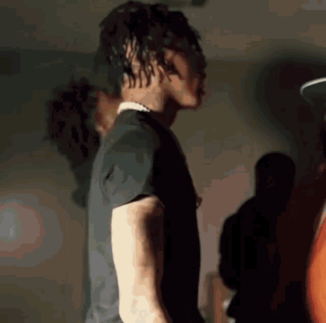 a man with dreadlocks is wearing a black shirt and a necklace .