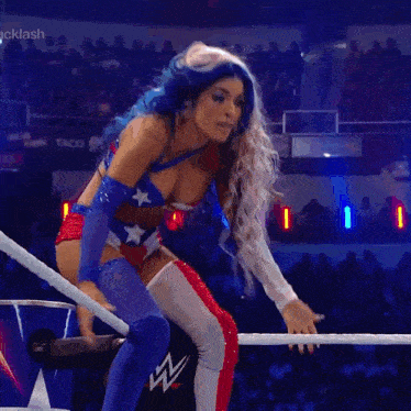 a woman in an american flag outfit is standing in a wrestling ring .