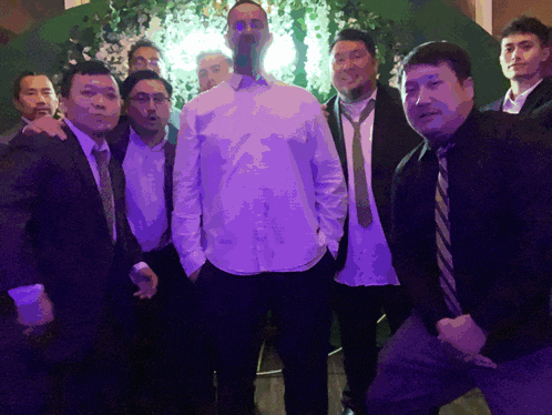 a group of men are posing for a picture with one man wearing a white shirt
