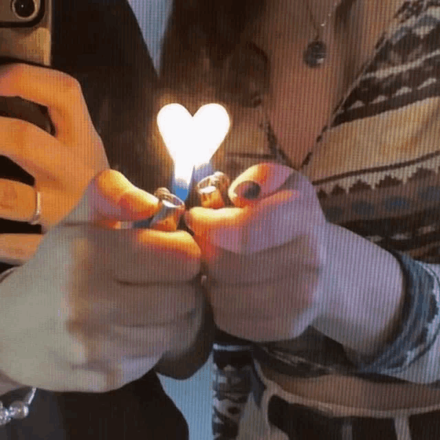 a person is lighting a heart shaped lighter in their hands .