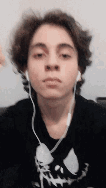 a young man wearing headphones and a black shirt with a skeleton on it