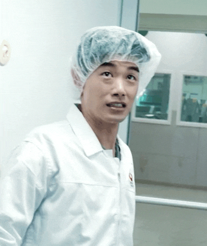 a man wearing a white lab coat and a plastic cap with the letter p on it