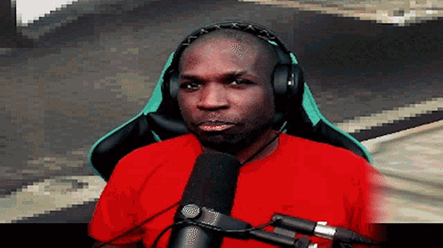 a man in a red shirt is sitting in front of a microphone