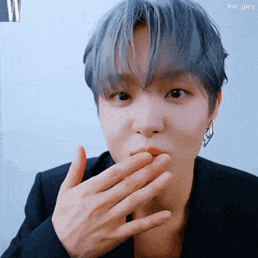 a close up of a person covering their mouth with their hand with tsr_jpeg in the corner