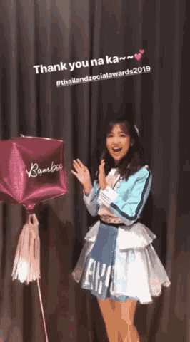a girl standing next to a pink balloon that says bamboo on it
