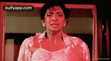 a woman in a red dress is crying in front of a window .