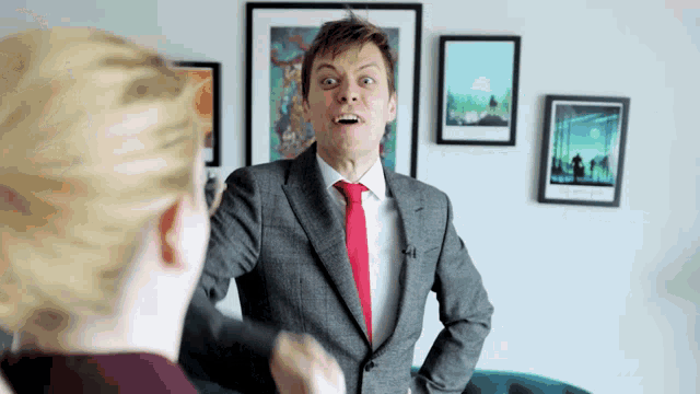 a man in a suit and red tie is standing in front of a woman