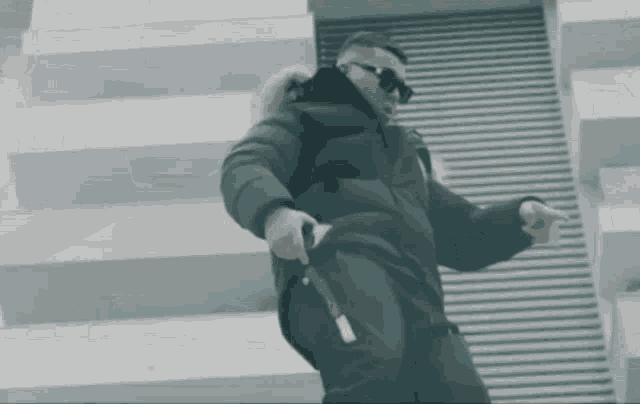 a man in a black jacket and sunglasses is dancing