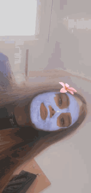 a girl wearing a blue face mask with a pink flower in her hair