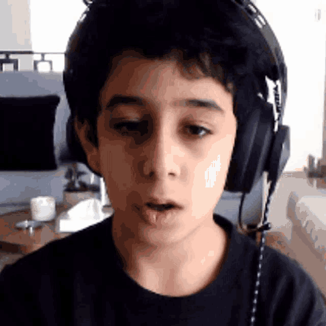 a young boy wearing headphones looks at the camera with his mouth open