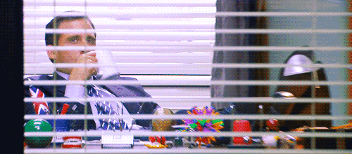 a man sits at a desk drinking a cup of coffee while looking out a window