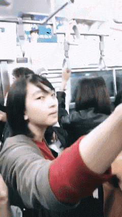 a woman in a red sweater is sitting in a crowded bus
