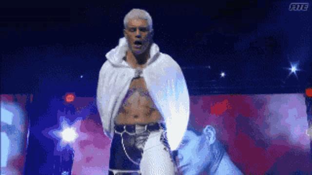 a man in a white cape is standing on a stage in front of a man .