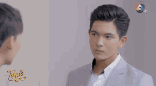 a man in a suit is looking at another man in a white shirt in front of a sign that says ' 7 hd '