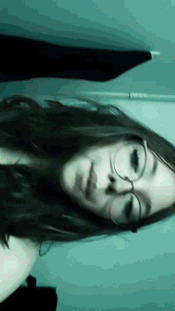 a girl with long hair and glasses is laying down