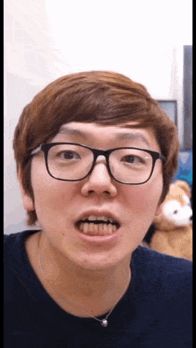 a young man wearing glasses and a blue shirt looks at the camera