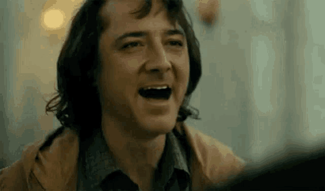 a close up of a man laughing with his mouth open in a movie scene .