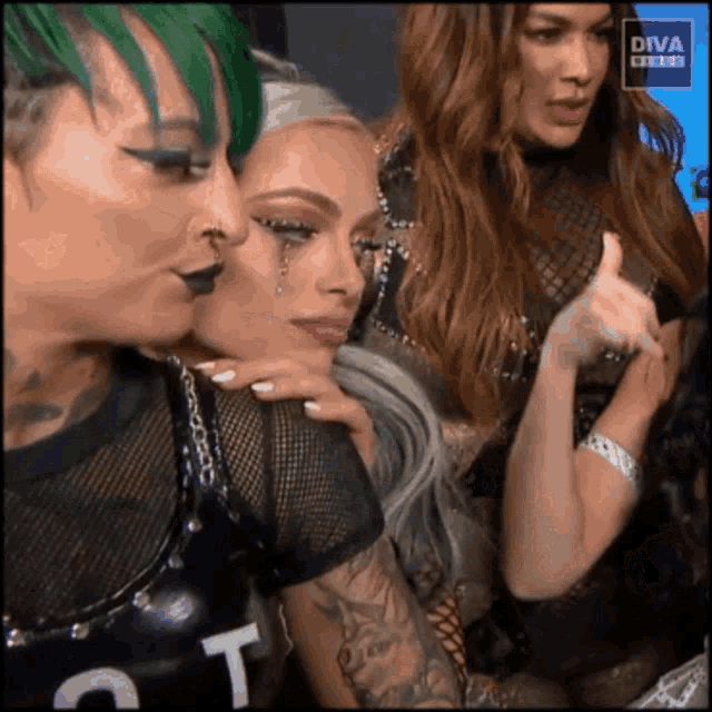 a woman with green hair is hugging another woman with tears coming out of her eyes