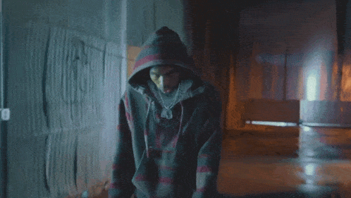 a man wearing a hoodie and gucci shorts is standing in a dark room