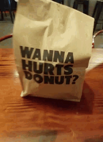 a bag that says wanna hurts donut is on a wooden table