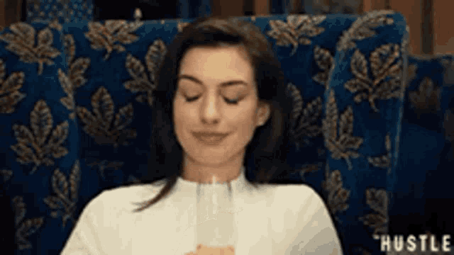 a woman is sitting in a chair with her eyes closed and drinking a glass of wine .