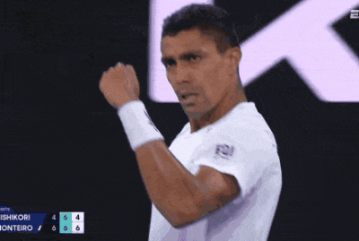 a man wearing a white shirt with the letters fqi on it holds his fist in the air