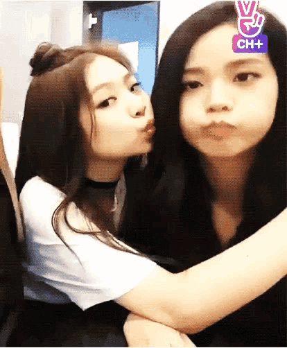 two girls are hugging each other and one of them is kissing the other .