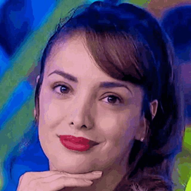 a close up of a woman 's face with her hand on her chin and red lipstick .