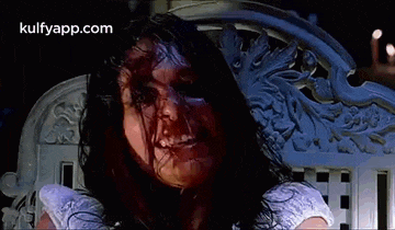 a woman with blood on her face is sitting on a white bench .