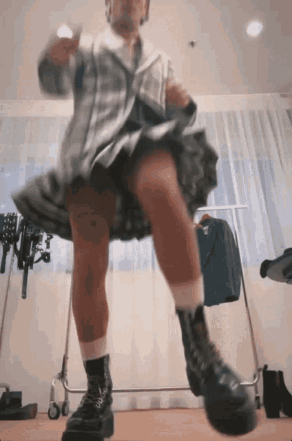 a woman in a plaid shirt and black boots is dancing