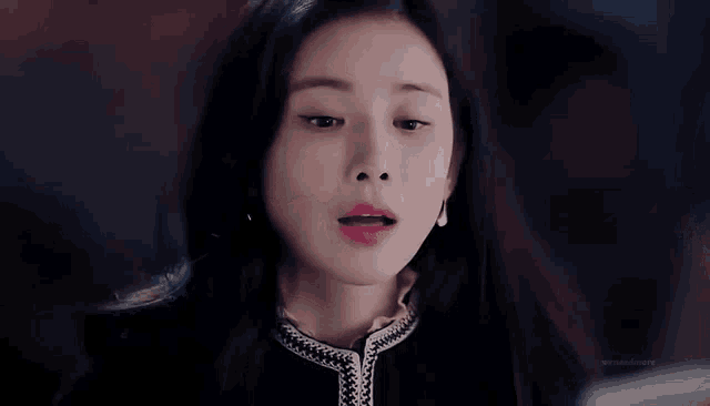 a close up of a woman 's face with her eyes closed . she is wearing a black jacket and earrings .