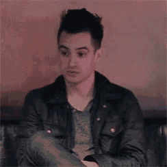 a man in a leather jacket is sitting with his arms crossed