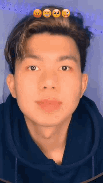 a young man wearing a blue hoodie with emojis on his head .