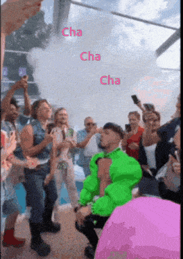 a man in a green shirt is dancing in front of a crowd with the words cha cha cha on the bottom
