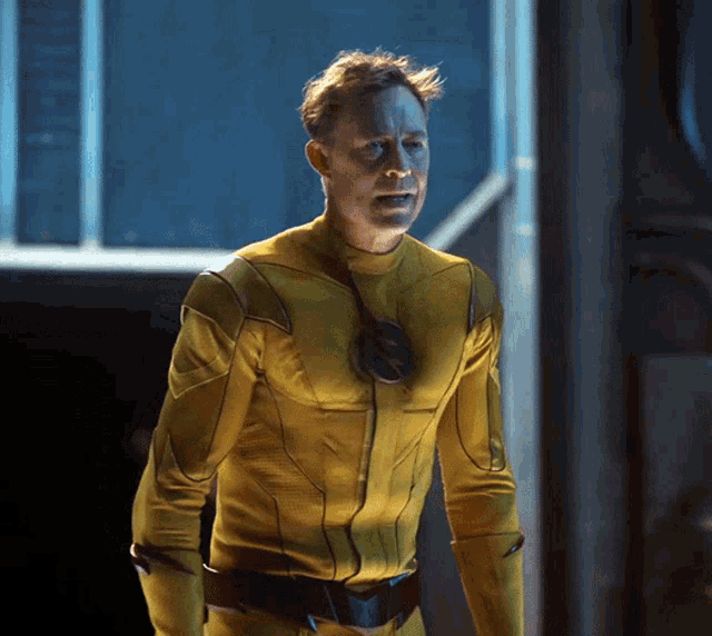 a man in a yellow superhero costume is standing in a dark room
