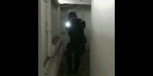 a person standing in a hallway with a flashlight