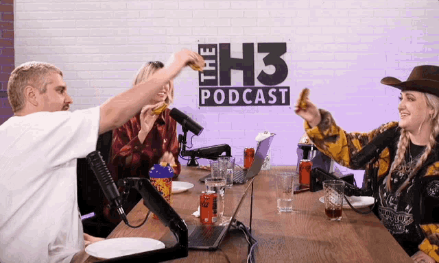 a group of people are sitting at a table in front of a sign for the h3 podcast