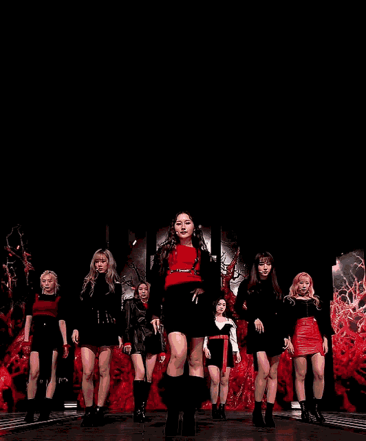 a group of girls are standing on a stage with a black background