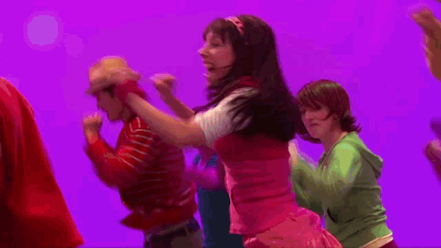 a group of people are dancing in front of a purple backdrop