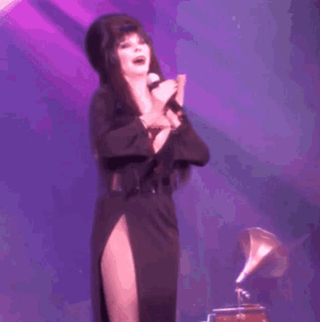 a woman is singing into a microphone on a stage